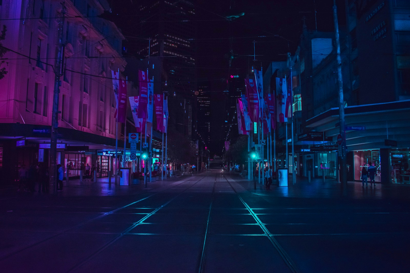 Rua urbana iluminada em tons azul e violeta durante a noite